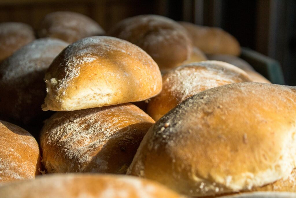 Close-up of freshly baked bread rolls in warm sunlight, highlighting the golden crusts and inviting texture.
