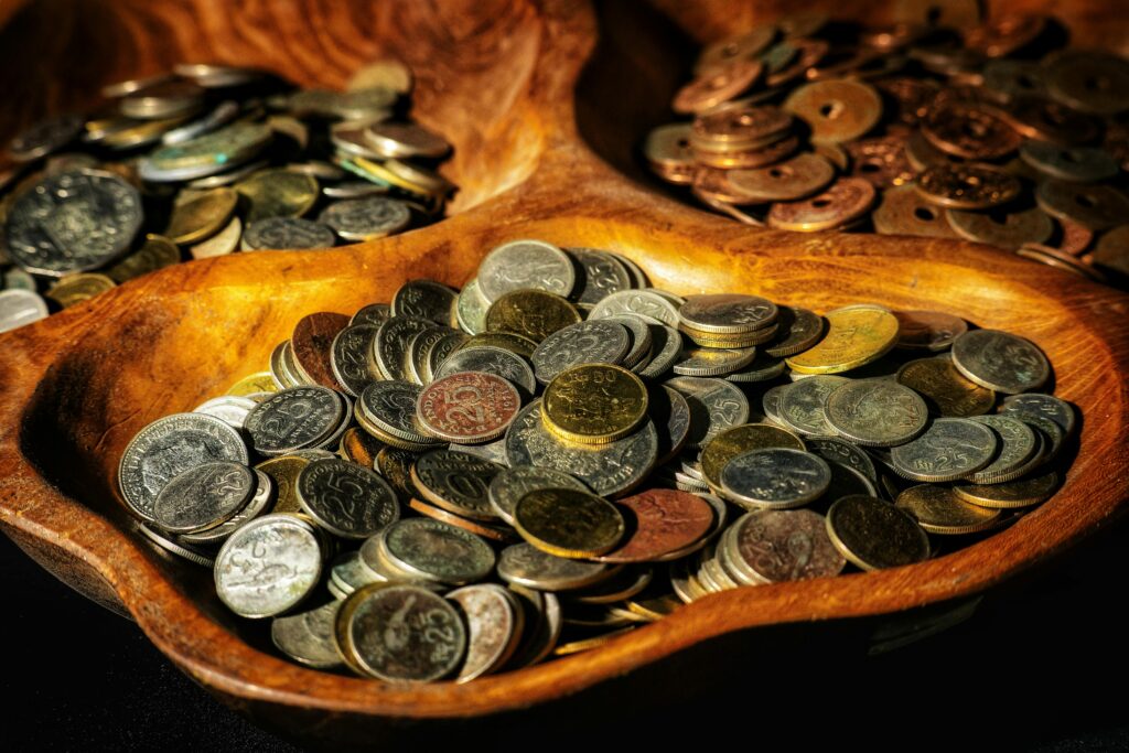 Indonesian coins of various denominations displayed in wooden bowls, showcasing currency diversity.