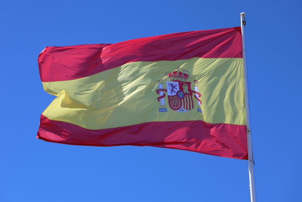 Vibrant Spanish flag waving against a clear blue sky in Cádiz, Andalucía.
