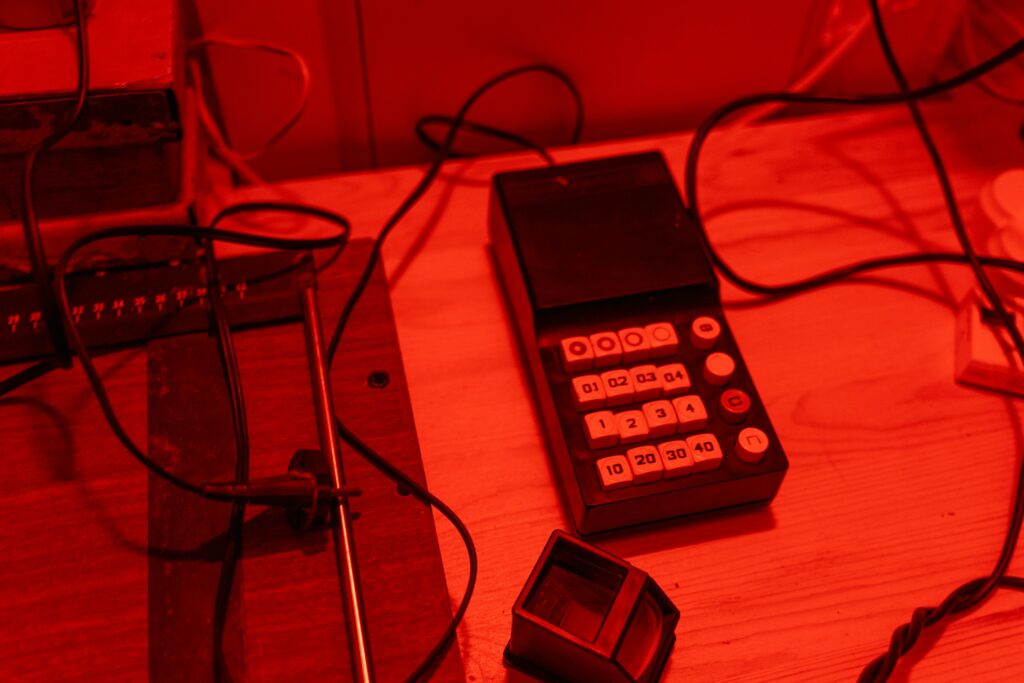 Darkroom workspace with vintage keypad and tools in red lighting.
