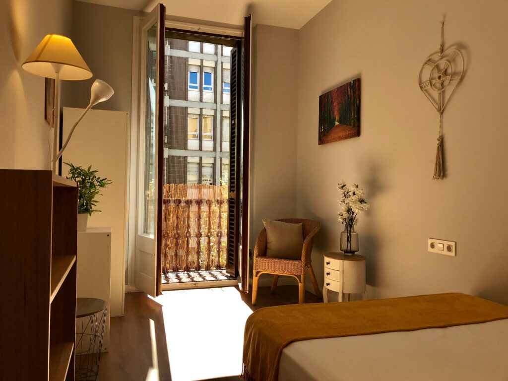 A sunlit bedroom with modern decor in a Barcelona apartment, offering a comfortable and stylish interior.