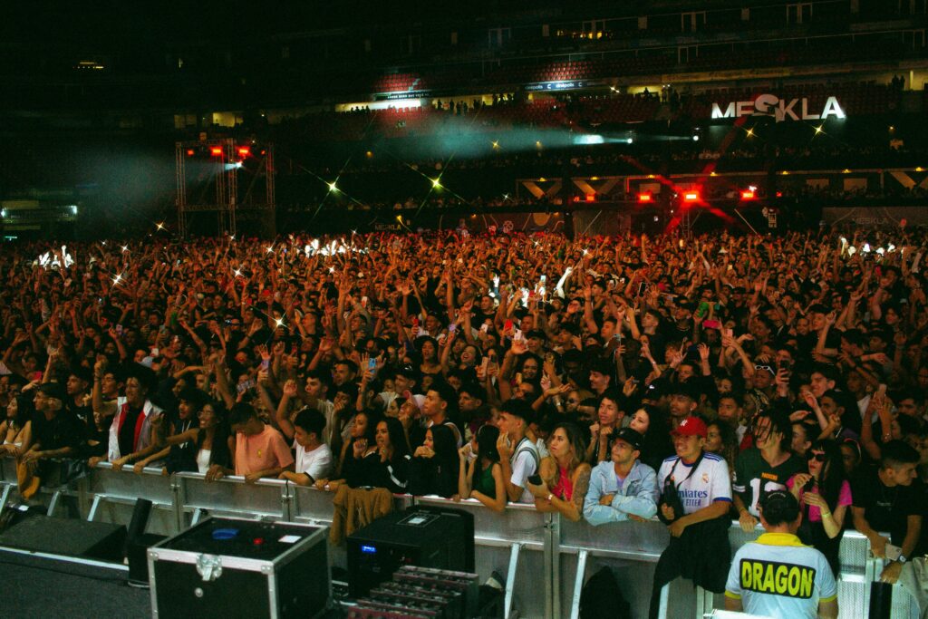 A vibrant concert with a large, enthusiastic crowd enjoying live music at night.