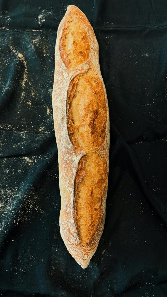 Crisp and fresh baguette laid on a dark background, top view angle for food enthusiasts.