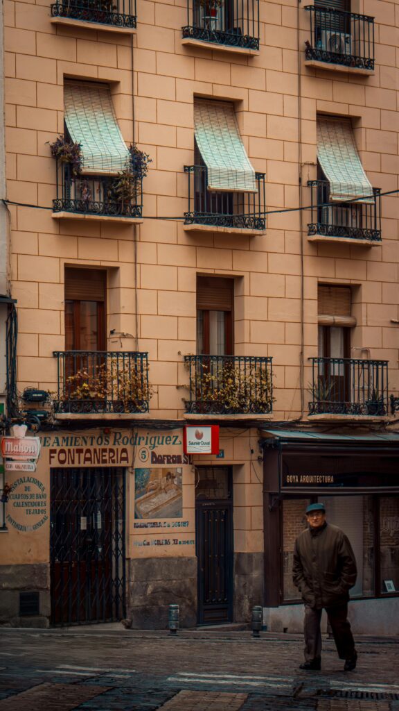 Old world charm in Madrid street with balconies and historic shops.