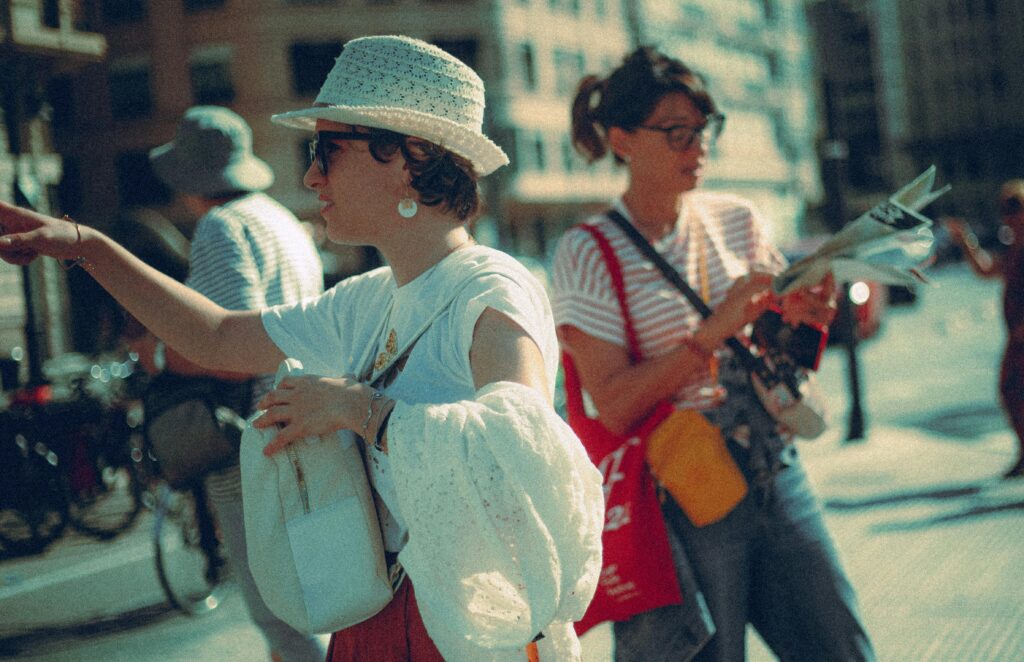 Two women enjoy a sunny day in the city, pointing and navigating with a map.