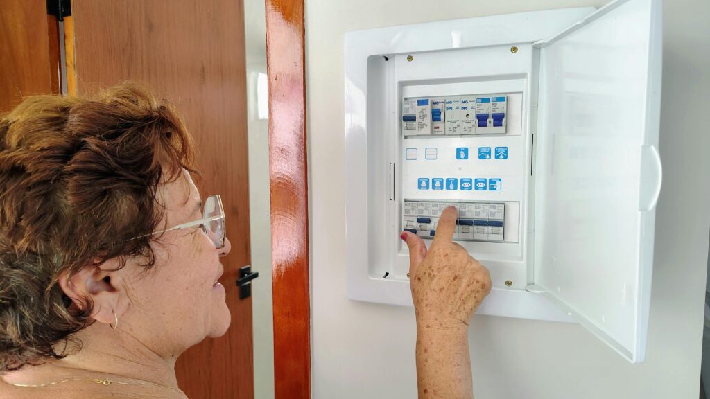 A senior woman is adjusting an electrical fuse panel indoors, demonstrating home safety.