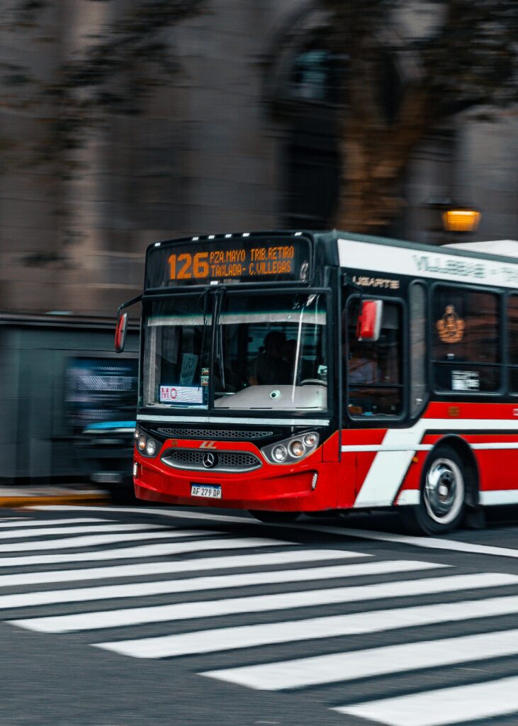 Dynamic capture of a red city bus crossing a street in an urban setting.